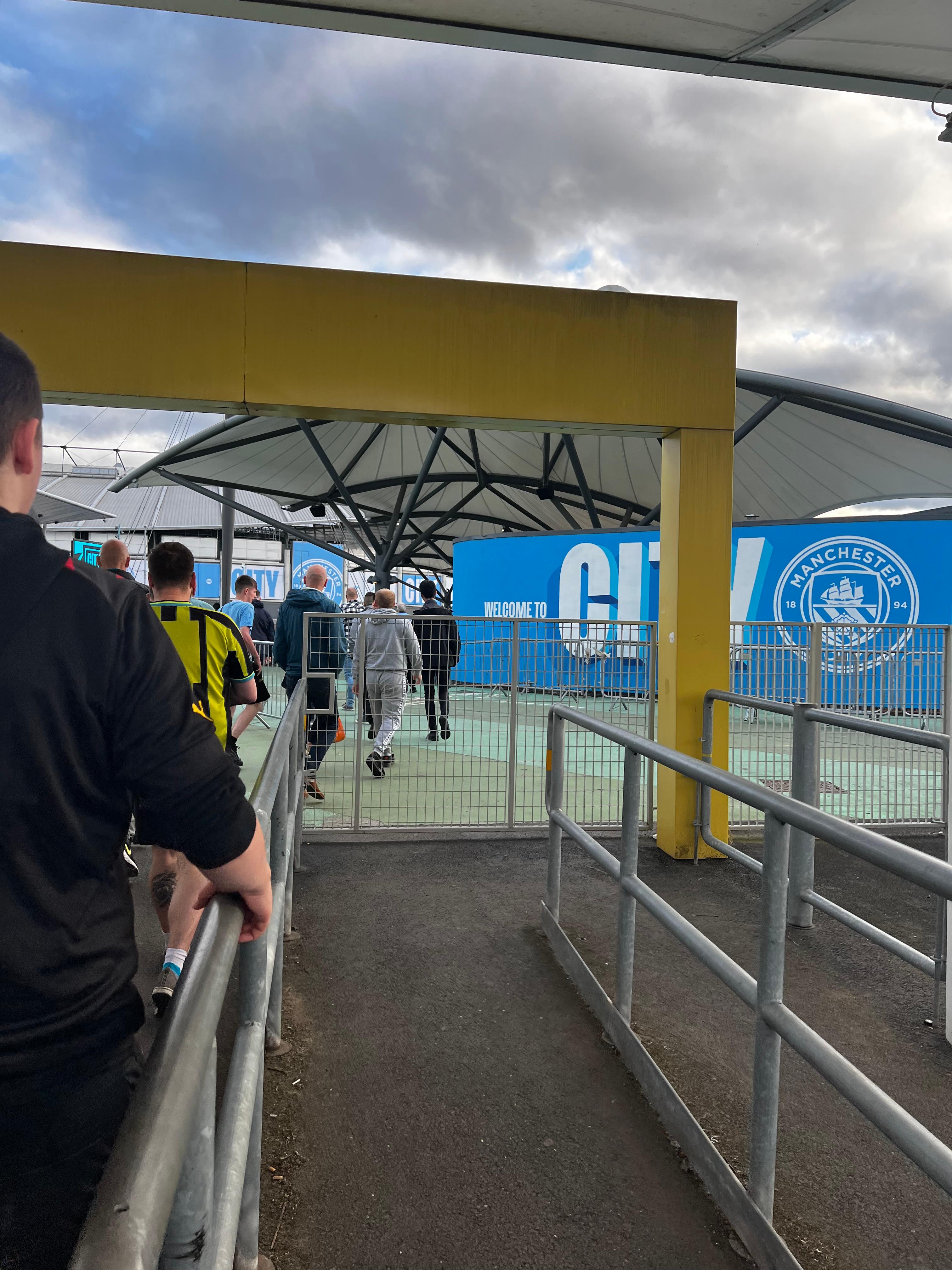 Etihad Stadium entrance Welcome to City sign Manchester City crest fans arriving matchday Premier League